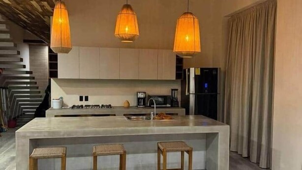 A modern kitchen with a central island, pendant lights, and a staircase. - Deisy TownHouse Oaxaca (San Pedro Mixtepec)
