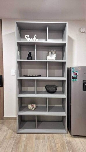 A grey shelving unit with decorative items and a refrigerator. - 103 Insurgentes Nayeli (Mexico City)