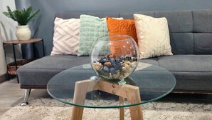 A glass coffee table with a bowl of pebbles on a wooden stand. - 103 Insurgentes Nayeli (Mexico City)