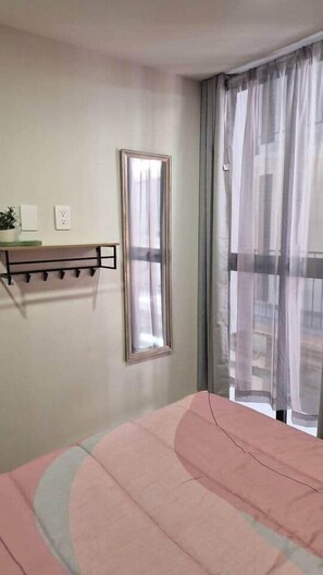 A bedroom with a bed, a bedside table, a mirror, and a window with curtains. - 103 Insurgentes Nayeli (Mexico City)