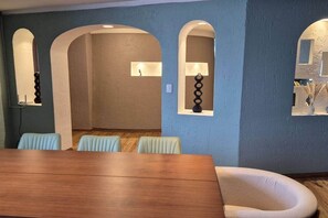 A dining area with a wooden table and four chairs, blue walls, and arched doorways. - Fabian (Rio de Janeiro) (Mexico City)