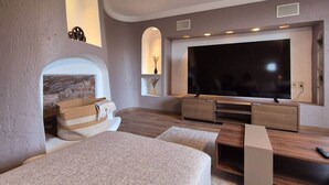 Un salon moderne doté d’un grand téléviseur à écran plat, d’un meuble de rangement en bois intégré et d’un coin salon confortable avec une cheminée.