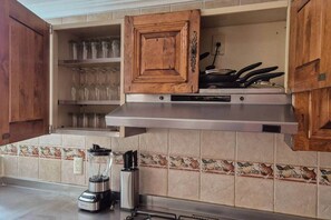 A kitchen with wooden cabinets, a stainless steel range hood, and a blender on the counter. - Fabian (Rio de Janeiro) (Mexico City)