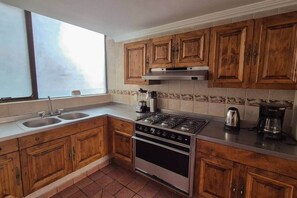 A kitchen with wooden cabinets, a stove, and a sink. - Fabian (Rio de Janeiro) (Mexico City)