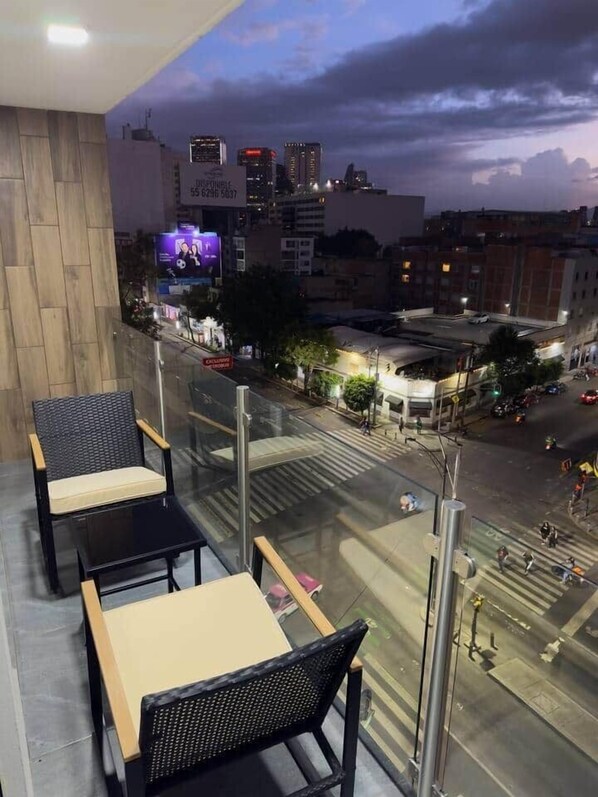 Un balcón con asientos y vista a la ciudad al anochecer.