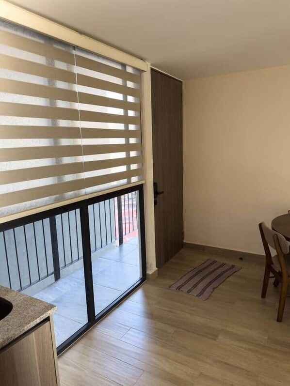 Een kamer met een schuifglasdeur die uitkomt op een buitenruimte, een eettafel met stoelen en een houten vloer.