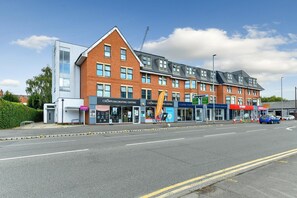 A multi-story building with various shops on the ground floor, including a Crown Decorating Centres and a Clarke Home. - Modern 2-Bed Near Trent Bridge & City Ground (Nottingham)