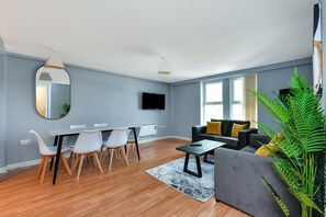 A modern living room with a dining area, a flat-screen TV, and a large window. - Modern 2-Bed Near Trent Bridge & City Ground (Nottingham)