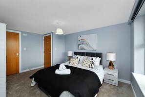 A hotel room with a bed, bedside tables, a wall art piece, and a door. - Modern 2-Bed Near Trent Bridge & City Ground (Nottingham)