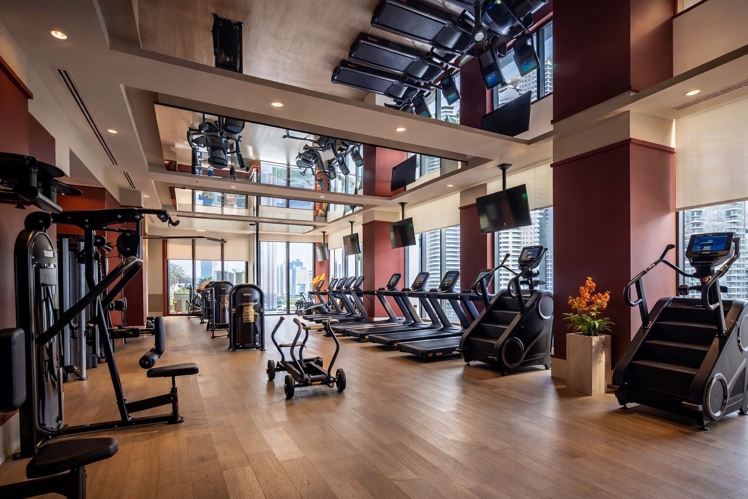 Un gimnasio espacioso con cintas de correr, máquinas de pesas y un ventanal que ofrece vistas a la ciudad.