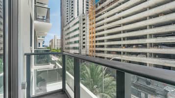 Un edificio alto con varios niveles de estacionamiento, una grúa de construcción y vistas a palmeras.
