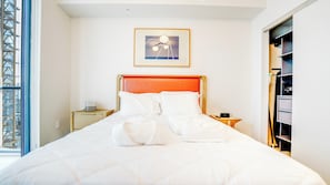 A neatly made bed with white linens, a framed picture above it, and a nightstand with a lamp. - N Miami Ave - Suites (Miami)
