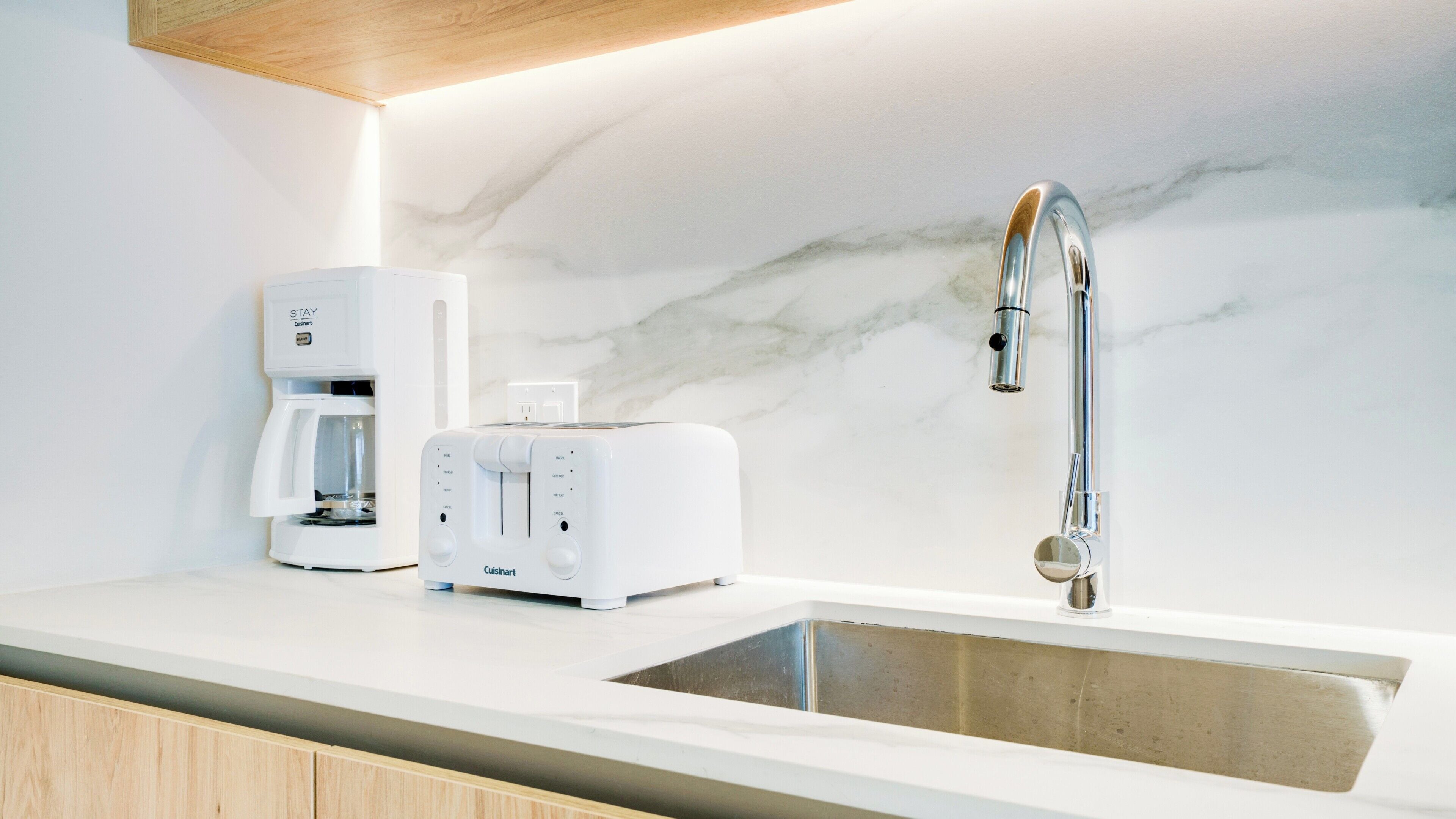 A kitchen with a built-in coffee maker, a toaster, and a modern faucet.