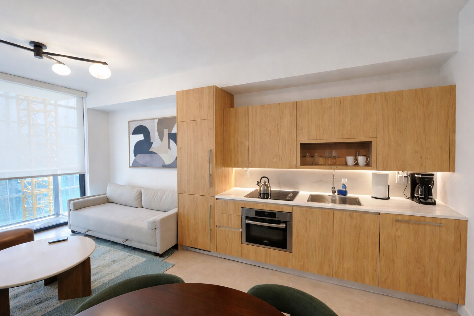 Una cocina moderna con armarios de madera, horno integrado, cafetera y comedor con mesa y sillas.