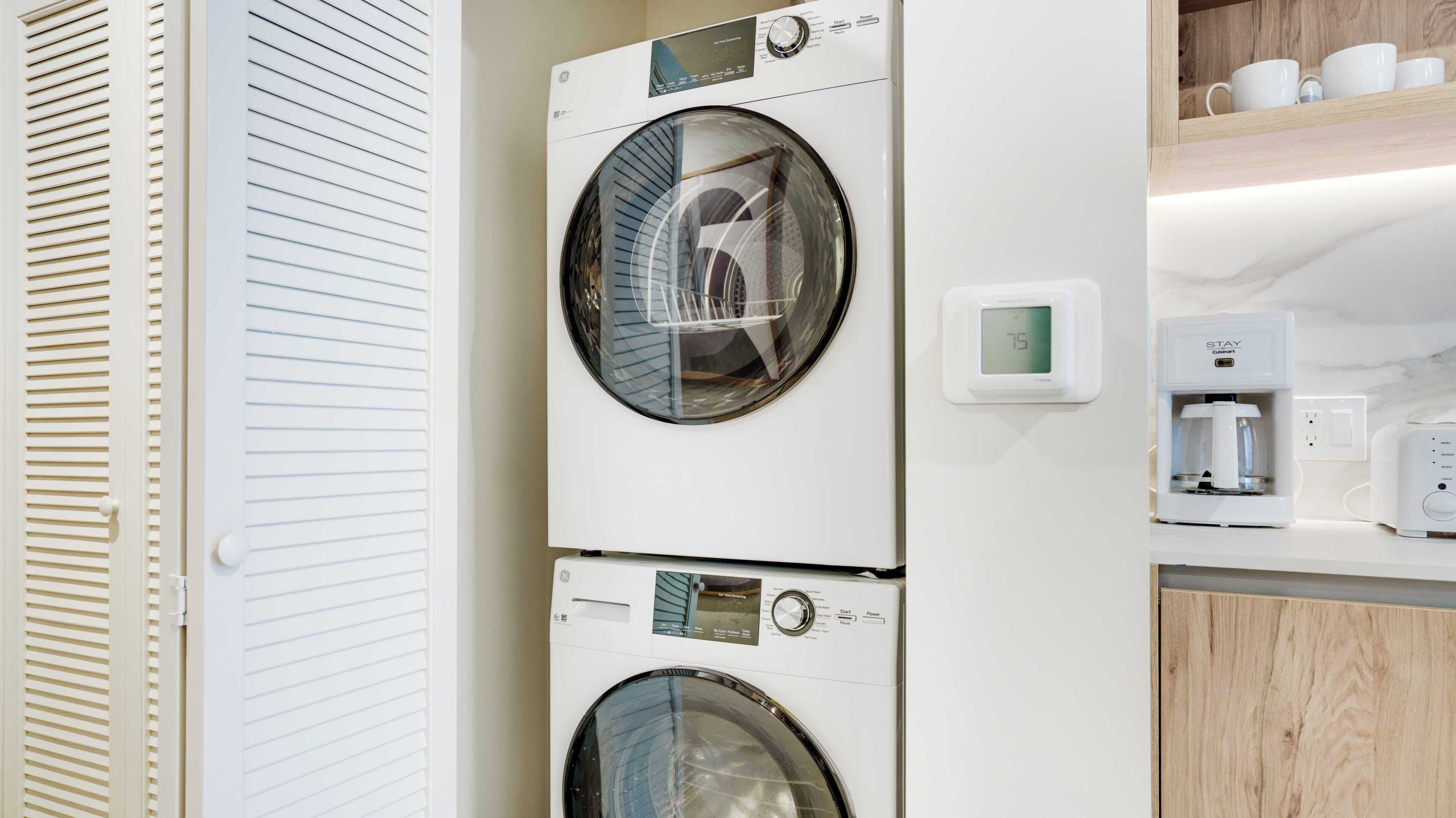 A laundry area with two stacked washing machines and a coffee maker.