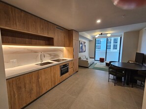 Una cocina moderna con armarios de madera, encimera de mármol y un comedor con mesa y sillas.