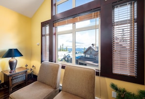 A room with two upholstered chairs, a lamp, and a window with blinds. - Spacious family ski in/ski out retreat with private hot tub (Beaverdell)