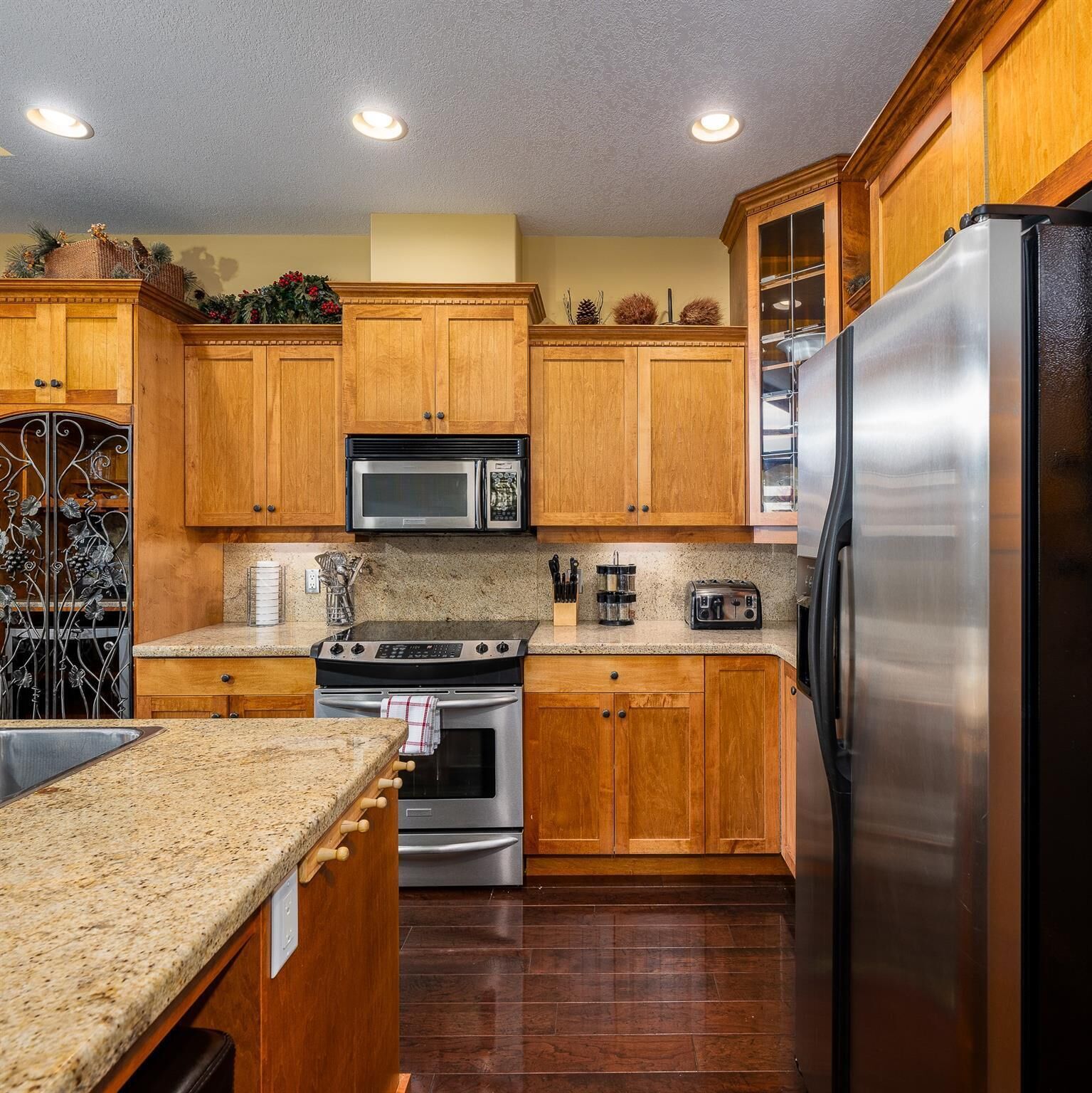 A kitchen with wooden cabinets, stainless steel appliances, granite countertops, and a built-in oven.