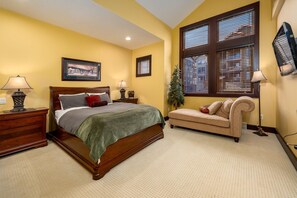 A bedroom with a bed, nightstands, a dresser, a sofa, and a window with blinds. - Spacious family ski in/ski out retreat with private hot tub (Beaverdell)
