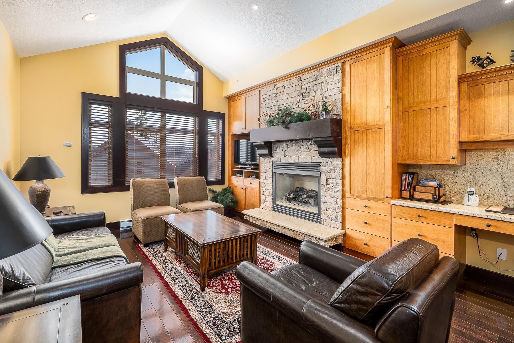 A living room with a fireplace, leather sofas, a coffee table, and wooden cabinets.