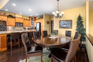 A dining area with a round table, chairs, and a chandelier. - Spacious family ski in/ski out retreat with private hot tub (Beaverdell)