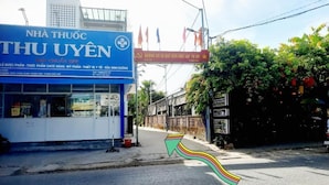A street view with a pharmacy named 'NHÀ THU UYEN' and a signboard with Vietnamese text.