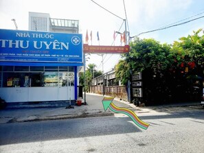 A street view with a pharmacy named 'NHÀ THU UYEN' and a signboard with Vietnamese text. - LANTANA Hue Homestay (Hue)