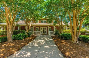 A two-story building with a central entrance, flanked by symmetrical landscaping and trees.