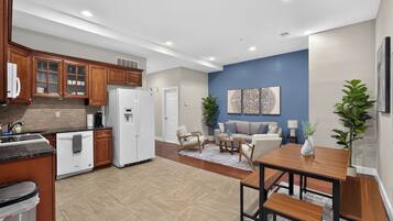 A modern kitchen with wooden cabinets, a white refrigerator, and a dining area with a wooden table and chairs.