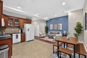 A modern kitchen with wooden cabinets, a white refrigerator, and a dining area with a wooden table and chairs. - Modern 2-bedroom by convention center -Elevator building (Philadelphia)