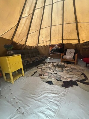 A cozy interior with a sofa, a small table, a painting, and a rug. - Unique Glamping tent with 2 twin beds in Sturgis South Dakota (Sturgis)