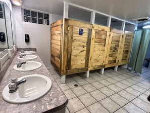 A public restroom with three sinks, wooden stalls, and a handicap-accessible sign. - Unique Glamping tent with 2 twin beds in Sturgis South Dakota (Sturgis)
