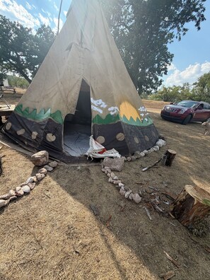 A tent with a painted design, surrounded by rocks and a tree stump. - Unique Glamping tent with 2 twin beds in Sturgis South Dakota (Sturgis)