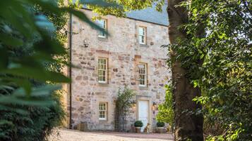 A stone building with a gravel driveway, a white door, and potted plants.