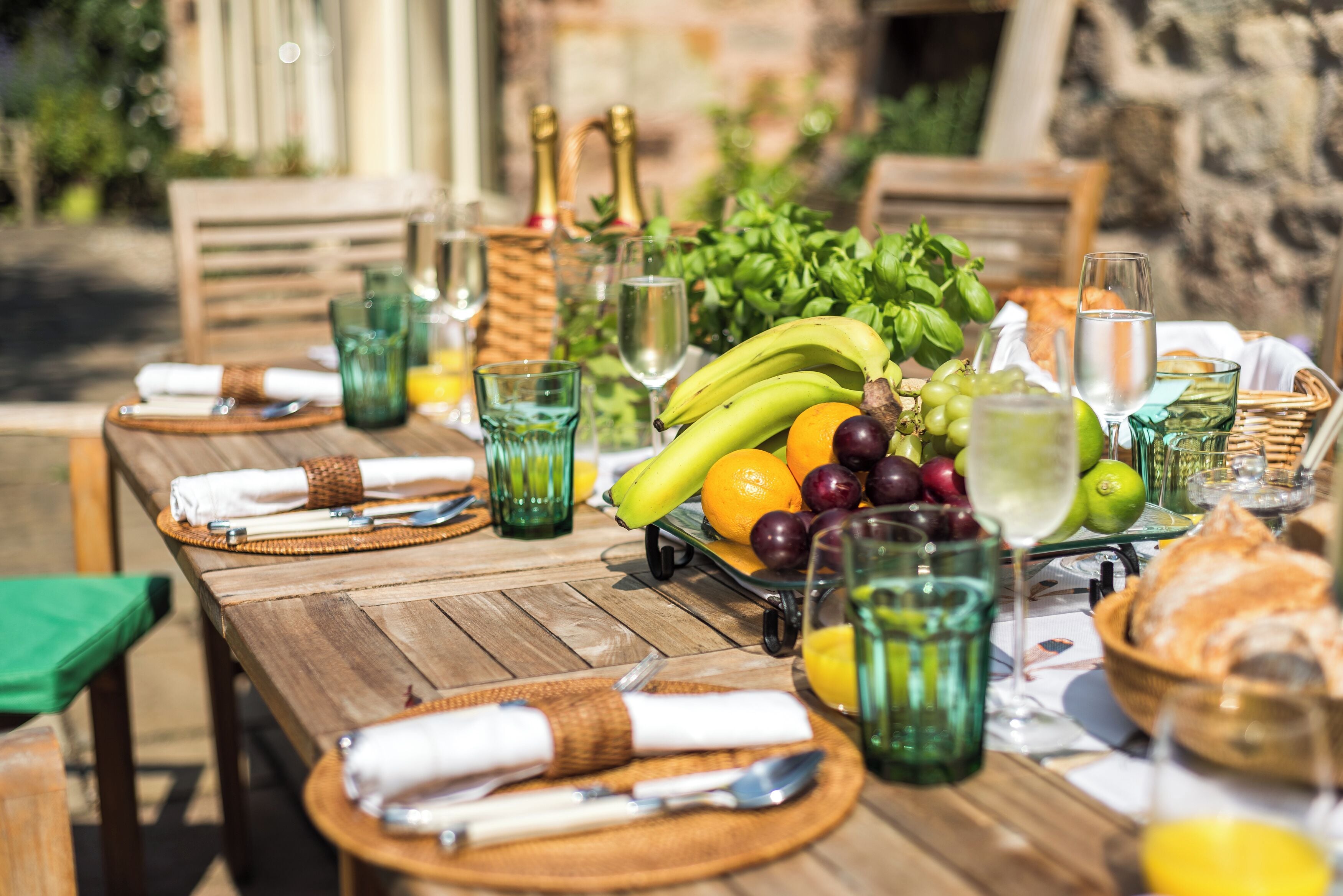 Ein Holztisch, reichhaltig belegt mit Obst, Gläsern und einer Champagnerflasche.
