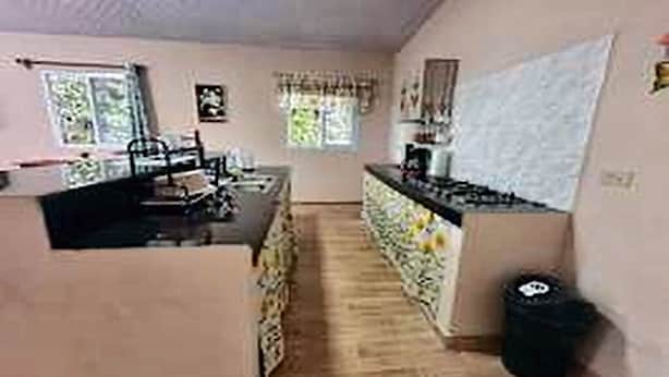 A kitchen with a central island, a dining area with chairs, and a trash bin.
