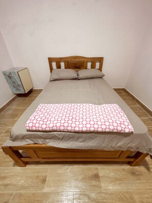 A single-bed room with a wooden headboard, a patterned bedspread, and a small bedside table with a lamp. - Urban Loft Nueva California (Nueva California)