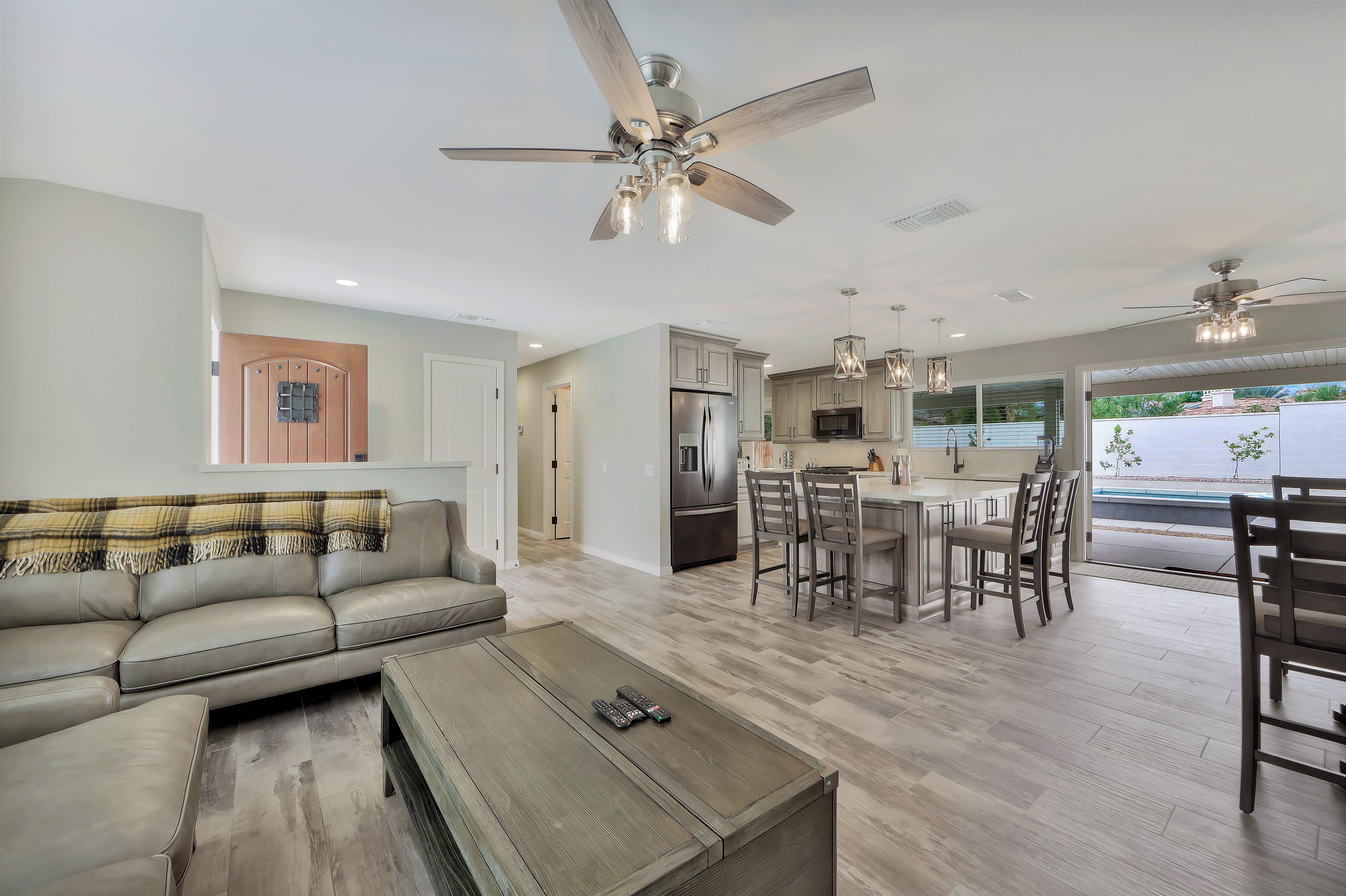 A modern kitchen with a central island, wooden flooring, and a dining area with chairs and a table.