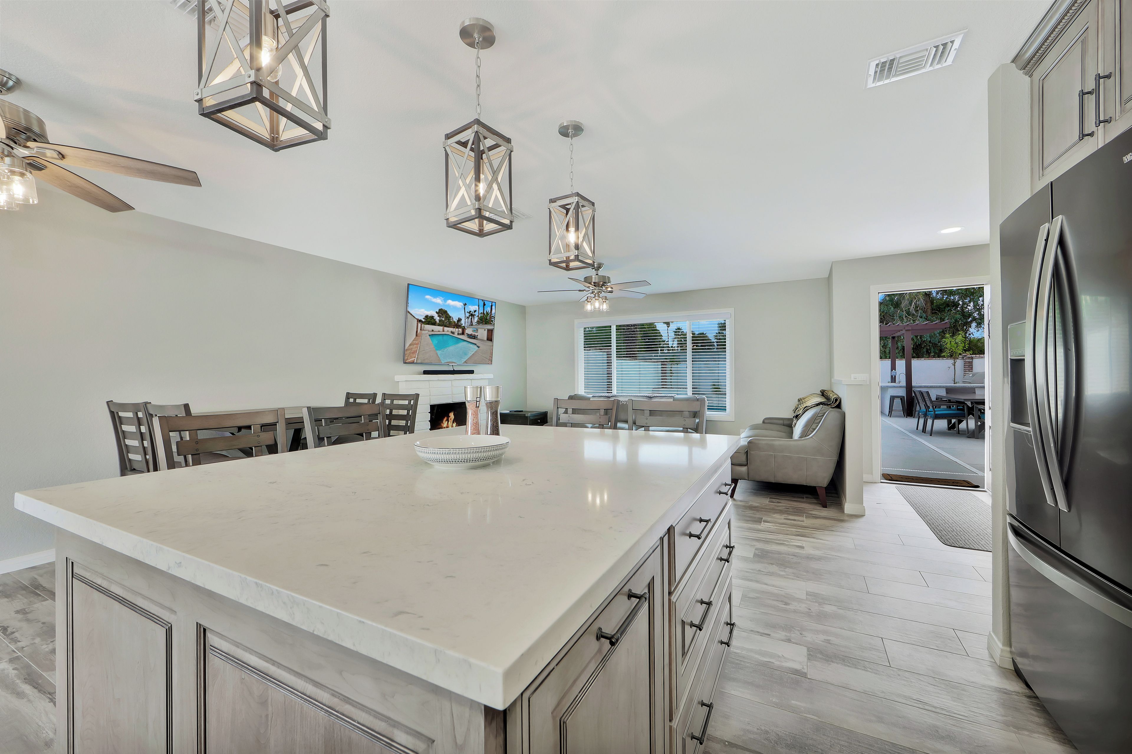 A modern kitchen with a large island, stainless steel appliances, and pendant lighting.