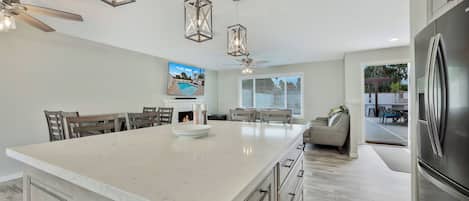 A modern kitchen with a large island, stainless steel appliances, and pendant lighting.