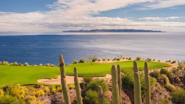 Un campo de golf costero con cactus y una vista despejada del océano.