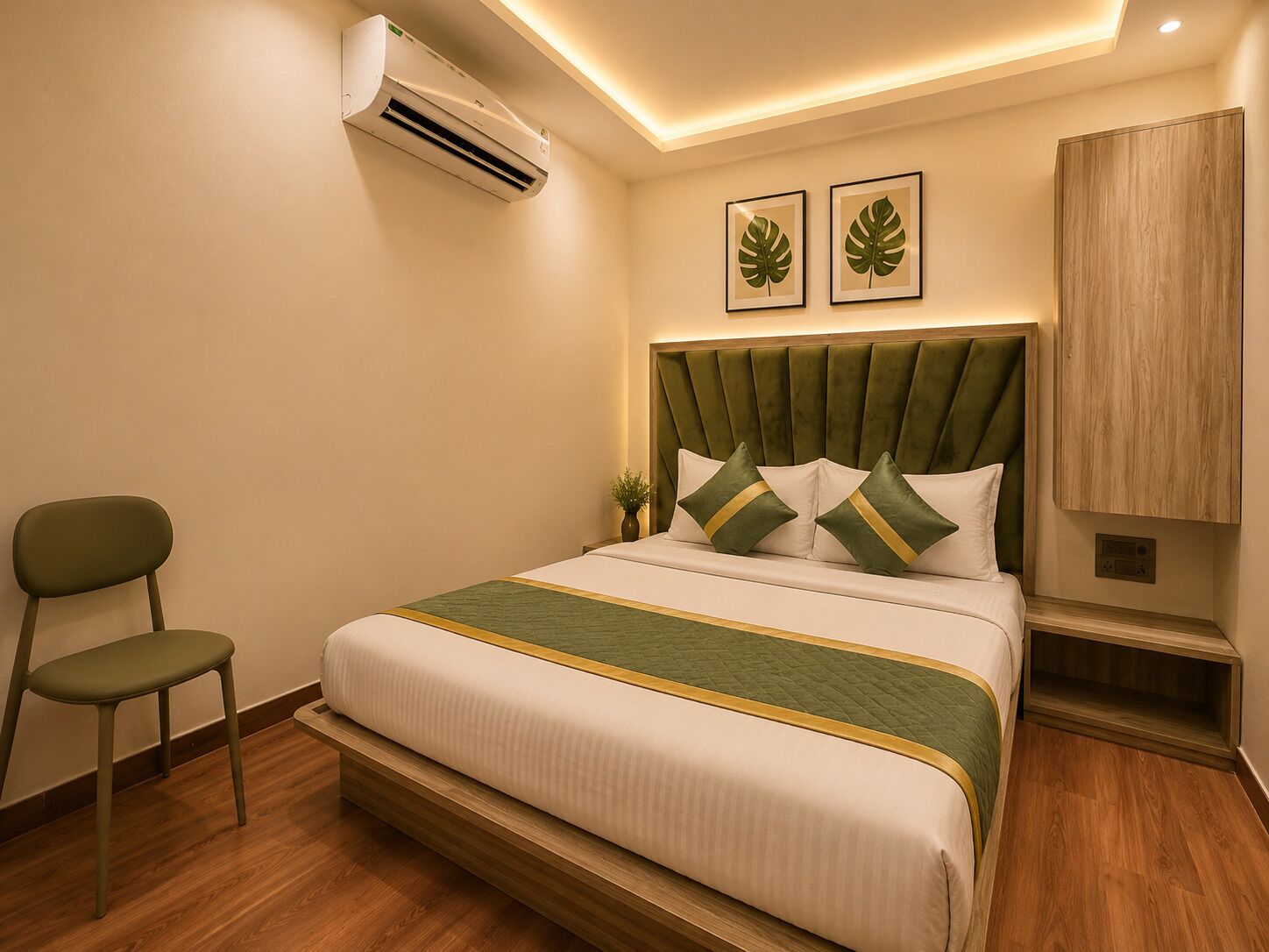 Una habitación de hotel con cama, una silla, un equipo de aire acondicionado y un mueble fijado a la pared.