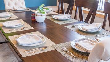 A dining table set with plates, cutlery, and napkins, surrounded by chairs.