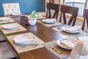 A dining table set with plates, cutlery, and napkins, surrounded by chairs.