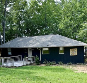 A small, single-story building with a dark blue exterior, a front porch, and a sign that reads 'Cozy Lake Escape.' - Cozy Lake Escape on Weiss Lake (Cedar Bluff)