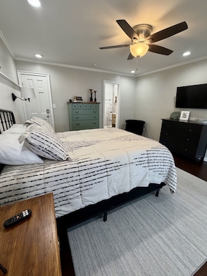 A bedroom with a bed, a dresser, a television, a ceiling fan, and a door. - Cozy Lake Escape on Weiss Lake (Cedar Bluff)