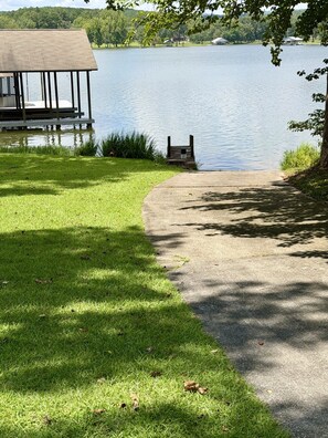 Une promenade au bord du lac, avec une terrasse en bois et un chemin en béton menant à un quai.