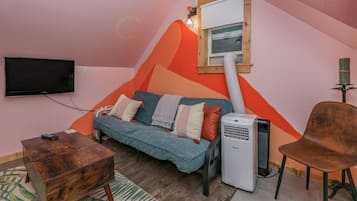 Une pièce confortable avec un canapé, un fauteuil, un téléviseur et un radiateur.