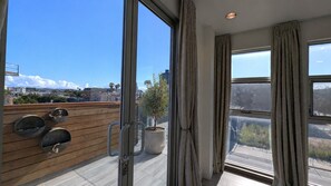A balcony with a wooden floor, a potted plant, and a view of a cityscape. - Luxury Condo with Walk-In Elevator and Patios (Los Angeles)