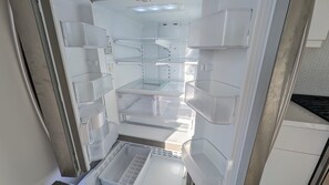 An interior of a refrigerator with multiple shelves and compartments. - Luxury Condo with Walk-In Elevator and Patios (Los Angeles)